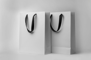 Paper shopping bags with ribbon handles on white background. Mockup for design