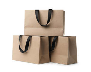 Paper shopping bags with ribbon handles on white background. Mockup for design