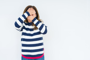 Beautiful middle age woman wearing navy sweater over isolated background Covering eyes and mouth with hands, surprised and shocked. Hiding emotion