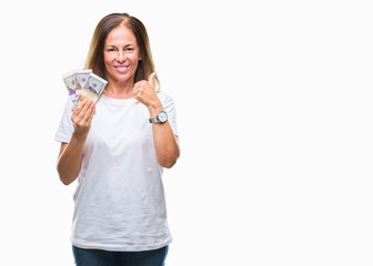 Middle age hispanic woman holding bunch of dollars over isolated background happy with big smile doing ok sign, thumb up with fingers, excellent sign