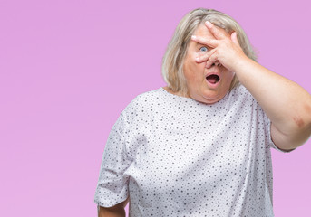 Senior plus size caucasian woman over isolated background peeking in shock covering face and eyes with hand, looking through fingers with embarrassed expression.