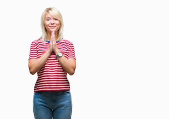 Young beautiful blonde woman over isolated background praying with hands together asking for forgiveness smiling confident.