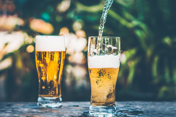 pouring beer to a glass close up in vintage tone background 