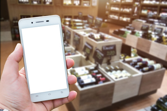 Men use hold smartphone blurred images of Various alcohol bottles in a row at the spirits store background.