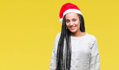 Young braided hair african american girl wearing christmas hat over isolated background with a happy and cool smile on face. Lucky person.