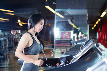 Fototapeta na wymiar Fitness Asian women performing doing exercises training the run on treadmill in sport gym interior and health club.