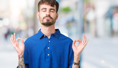 Young handsome man over isolated background relax and smiling with eyes closed doing meditation gesture with fingers. Yoga concept.