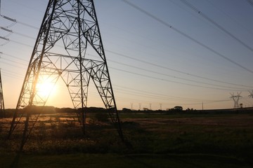 Electric power transmission tower at sunset.   Torre de transmissão de energia elétrica no pôr-do-sol. © Leidiane