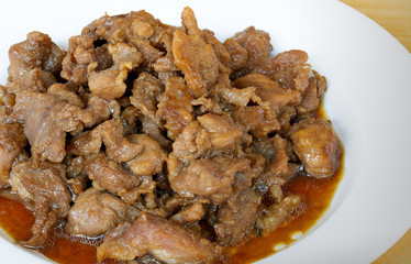 Stir fry pork slice with coconut sugar sprinkle with fried shallot slice (Sweet pork) in white dish on wooden table, delicious Thai food
