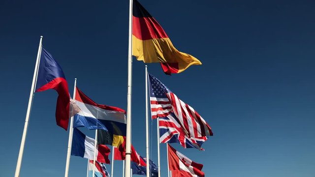 National flags together flying in slow motion on blue sky background