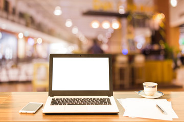 Mockup image of laptop with blank white screen on wooden table blurred images In the coffee shop at...