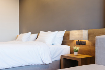 Close-up of white pillow on bed decoration with light lamp in hotel bedroom interior.