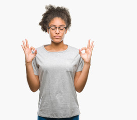 Young afro american woman wearing glasses over isolated background relax and smiling with eyes closed doing meditation gesture with fingers. Yoga concept.