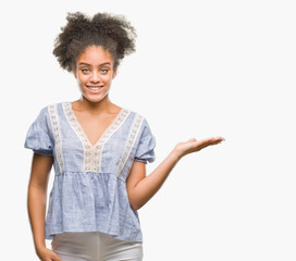 Young afro american woman over isolated background smiling cheerful presenting and pointing with palm of hand looking at the camera.