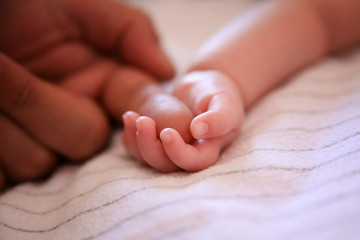 baby holding father's finger