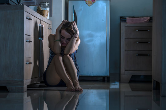 young depressed and overwhelmed woman desperate at home kitchen floor feeling sad and scared suffering depression and anxiety problem domestic violence concept