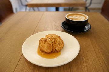 Homemade scone with honey syrub serving with hot coffee latte