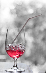 Red soda with ice in design glass over blurred backgrouond, vintage filter effect