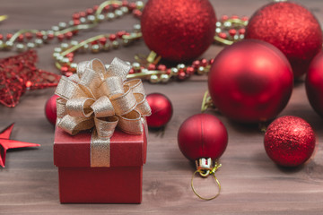 Red gift box with golden ribbon, soft blur backgound with red balls at top area