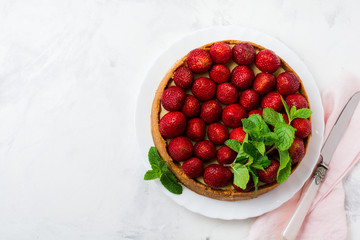 Cheesecake with fresh strawberries and mint on white plate on gray concrete background. Top view.