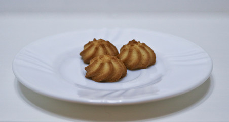 Three delicious cookies on a white dish. Culinary masterpieces.