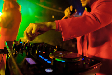 Dj mixes the track in the nightclub at party. In the background laser light show