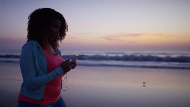 Voluptuous young Ethnic African American female doing gentle fitness for burning calories with wearable technology and ear buds  