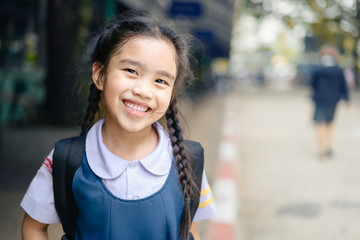 back to school. Happy smiling girl from elementary school at the school yard.