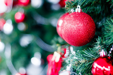 Closeup of red bauble hanging from a decorated Christmas tree. Happy new year concept.