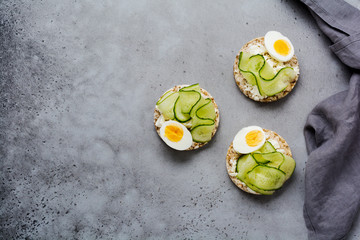Cucumber, egg and curd cheese sandwiches on gray concrete background. Top view.