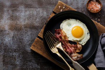 Traditioneel Engels ontbijt met gebakken eieren en spek in gietijzeren pan op donkere betonnen ondergrond. Bovenaanzicht.