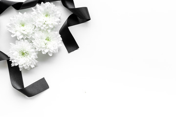 Funeral symbols. White flower near black ribbon on white background top view copy space