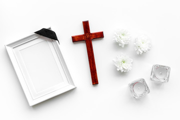 Funeral. Mockup of portrait of the deceased, of dead person. Frame with black ribbon near flowers, candles and cross on white background top view