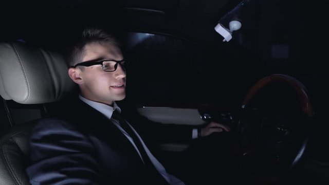 Angry businessman furiously hitting steering wheel in car at nighttime, problems