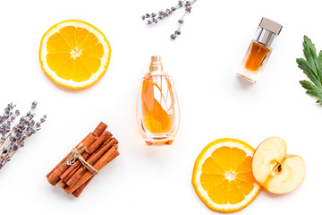 Sweet perfume with fruit fragrance. Bottle  of perfume near apple, orange, lavender, cinnamon on white background top view