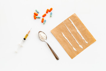 Take drugs, drugs addiction concept. White powder like heroine or cocaine, drug tracks pills, spoon, syringe on white background top view