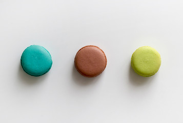 Turquoise, brown and green macarons on the white table. Top view, flat lay, copy space
