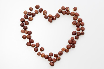 Heart shape from hazelnut on white background. Flat lay, top view, copy space