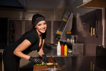 female chef preparing food in the kitchen of the restaurant Burger