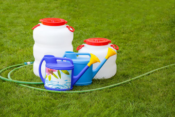 Plastic barrel, watering cans, hose, summer, green background