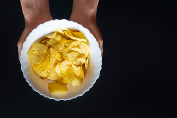 top view of hands holding a white plate with chips snacks  f