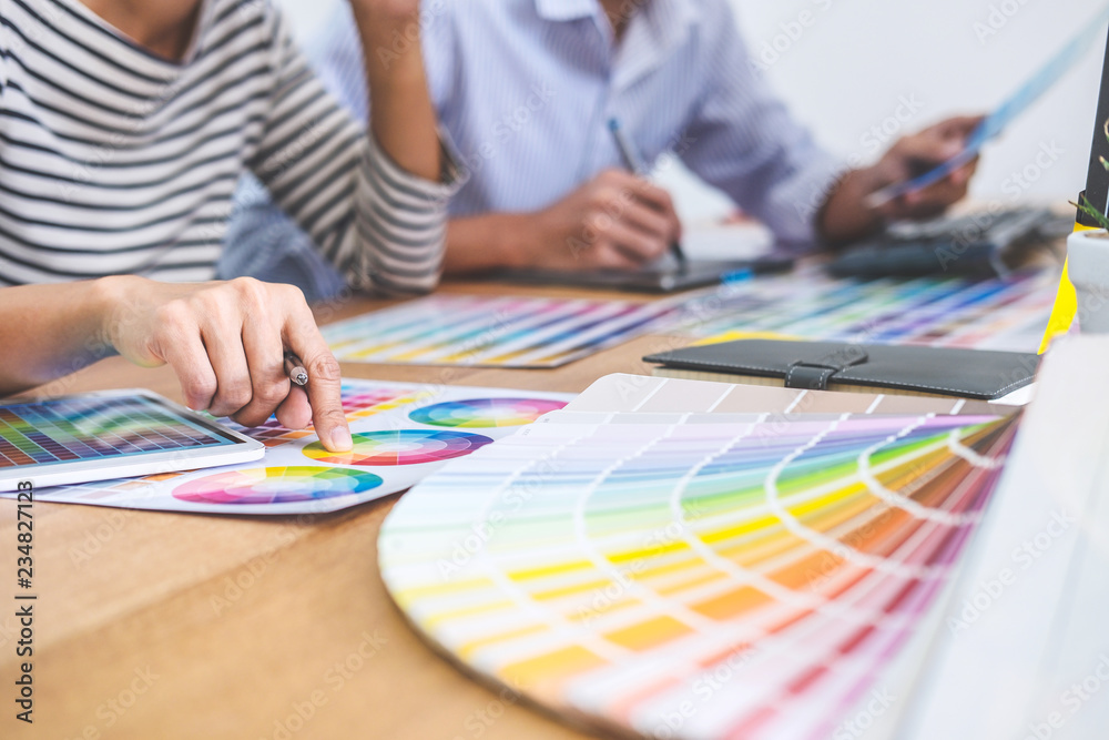 Aufkleber Two colleagues creative graphic designer working on color selection and drawing on graphics tablet at workplace, Color swatch samples chart for selection coloring