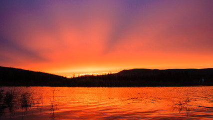 Fototapeta premium Rays of the setting sun over the lake