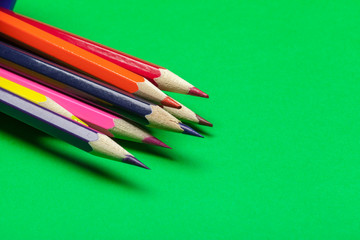 Colorful pencils on a bright green paper background
