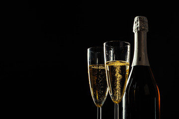 bottle of champagne and glasses over dark background