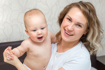 mother is playing with her baby son in the bedroom
