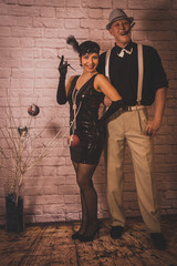 a girl with short black hair with a bandage with sequins and feathers on her head in a dress with sequins in the Chicago style of 20 years, with a man in a white shirt with suspenders and a black hat