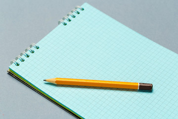 Short worn pencil with notepad on gray desk