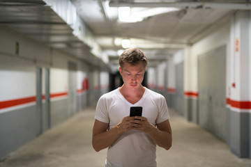 Young Handsome Man Using Phone Along The Corridor