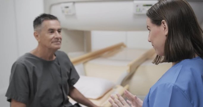 Nurse Talking To Elderly Man As Patient In Hospital Laboratory